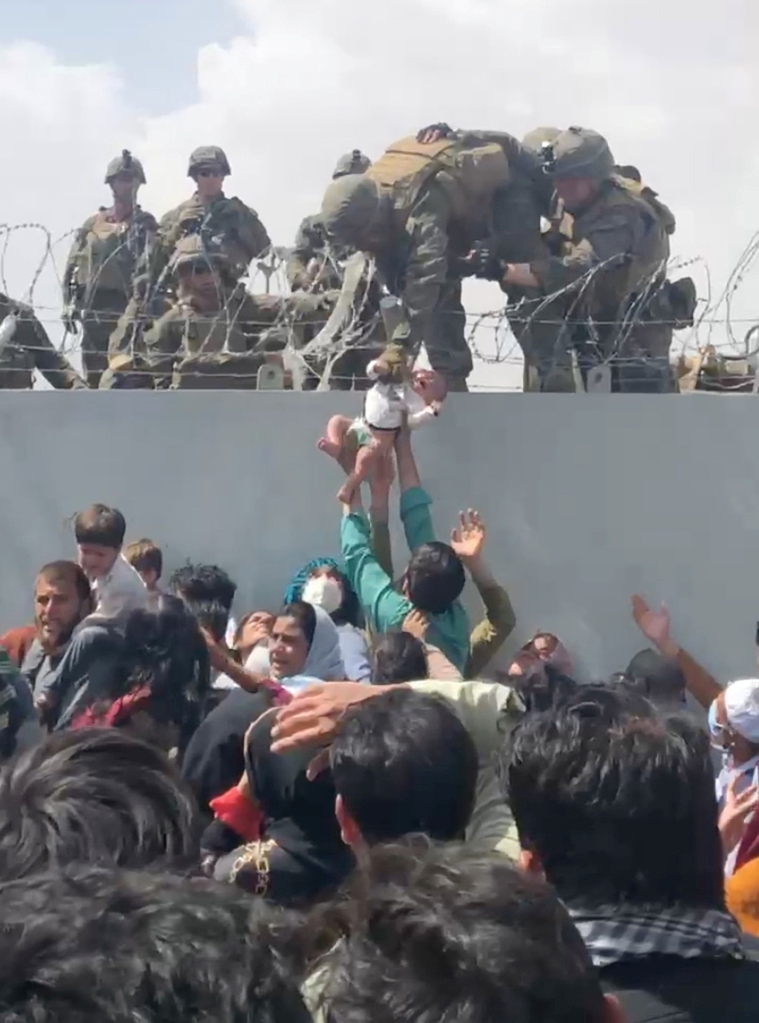 
A baby is handed over to the American army over the perimeter wall of the airport for it to be evacuated, in Kabul, Afghanistan, August 19, 2021