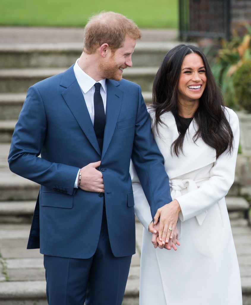 Prince Harry and Meghan Markle holding hands and smiling. 