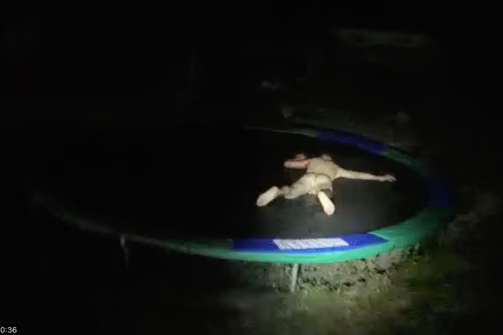 The nude man lies on the trampoline.
