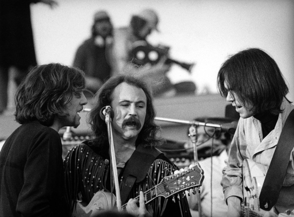 Graham Nash, David Crosby and Neil Young of Cosby Stills Nash and Young perform onstage at The Altamont Speedway on December 6, 1969 in Livermore, California.