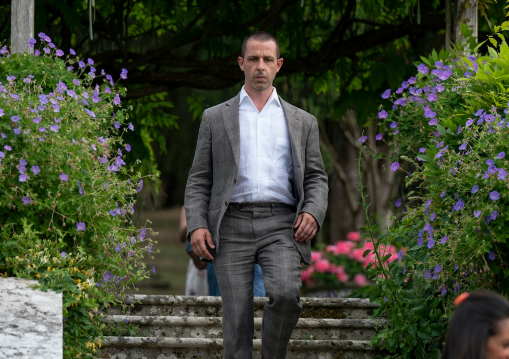 Jeremy Strong walking down stone steps looking serious. 