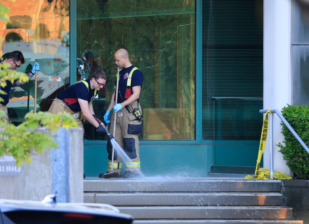 Members of the Louisville Fire Department clean steps of the Old National Bank in front of windows full of bullet holes.