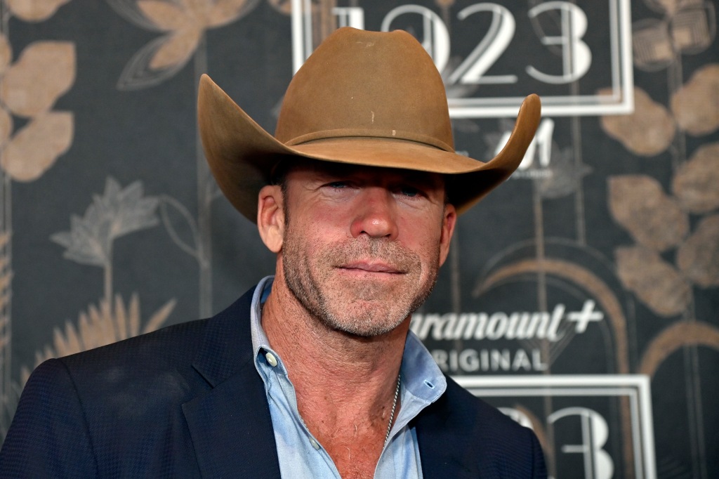 Taylor Sheridan smiling wearing a cowboy hat. 