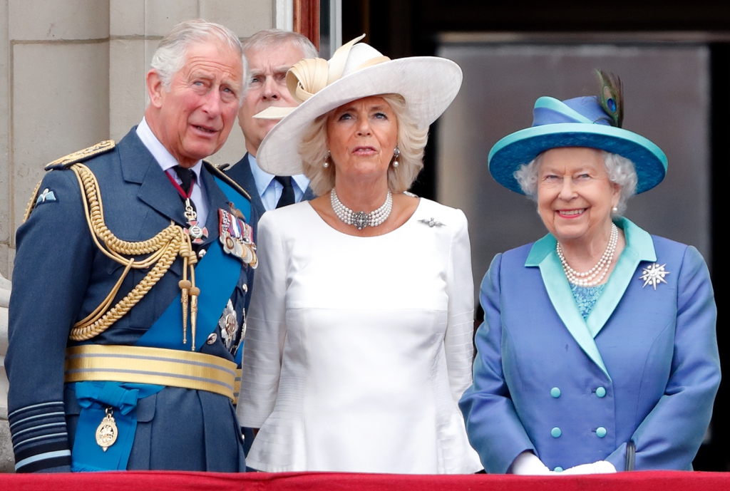 King Charles, Queen Consort Camilla, and Queen Elizabeth II standing together smiling. 