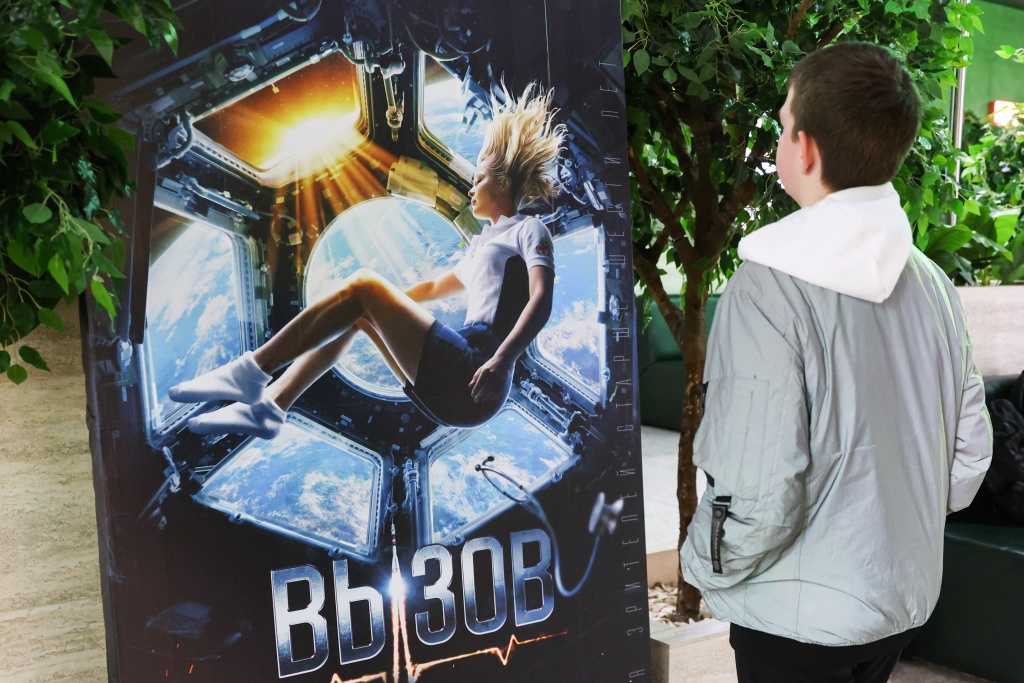 A man approaches a poster of the 2023 Russian drama film The Challenge.