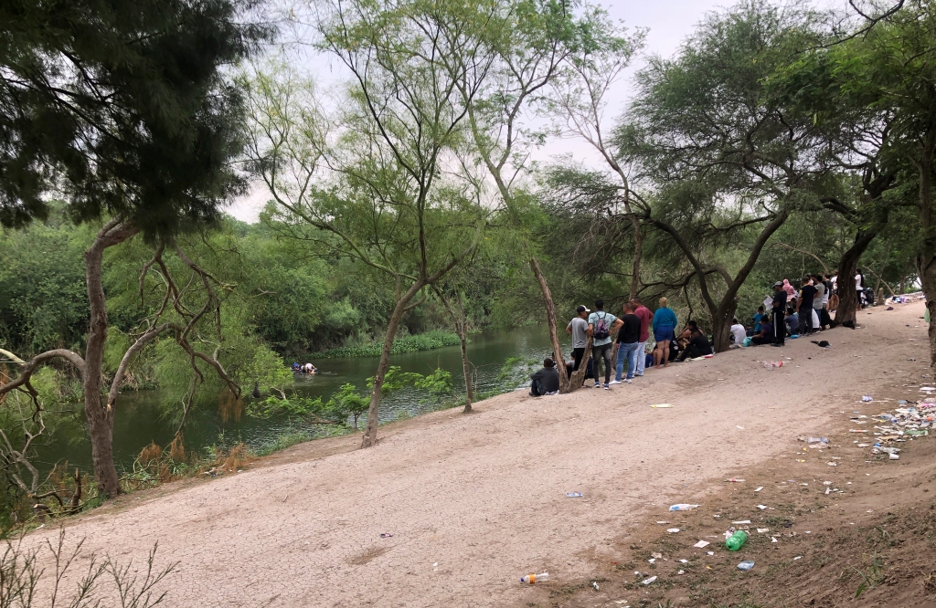 Migrants wait to cross river