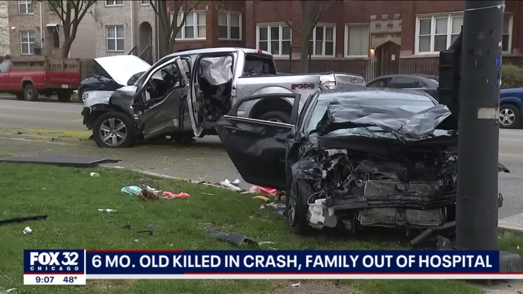 Mangled pickup truck stands in middle of street, while crumbled up car is partially on lawn 