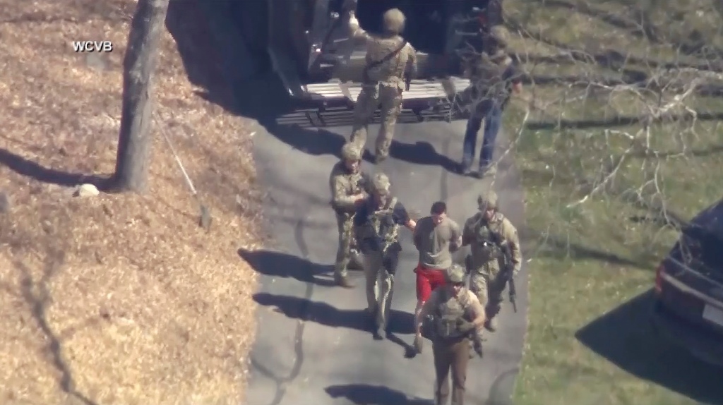 This image made from video provided by WCVB-TV, shows Jack Teixeira, in T-shirt and shorts, being taken into custody by armed tactical agents on Thursday, April 13, 2023, in Dighton, Mass.