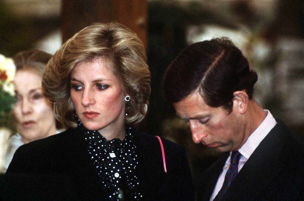 Princess Diana and Prince Charles standing next to each other looking serious. 