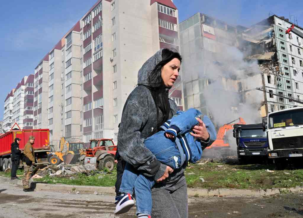 A woman rushes young child away from burning Uman high rise.