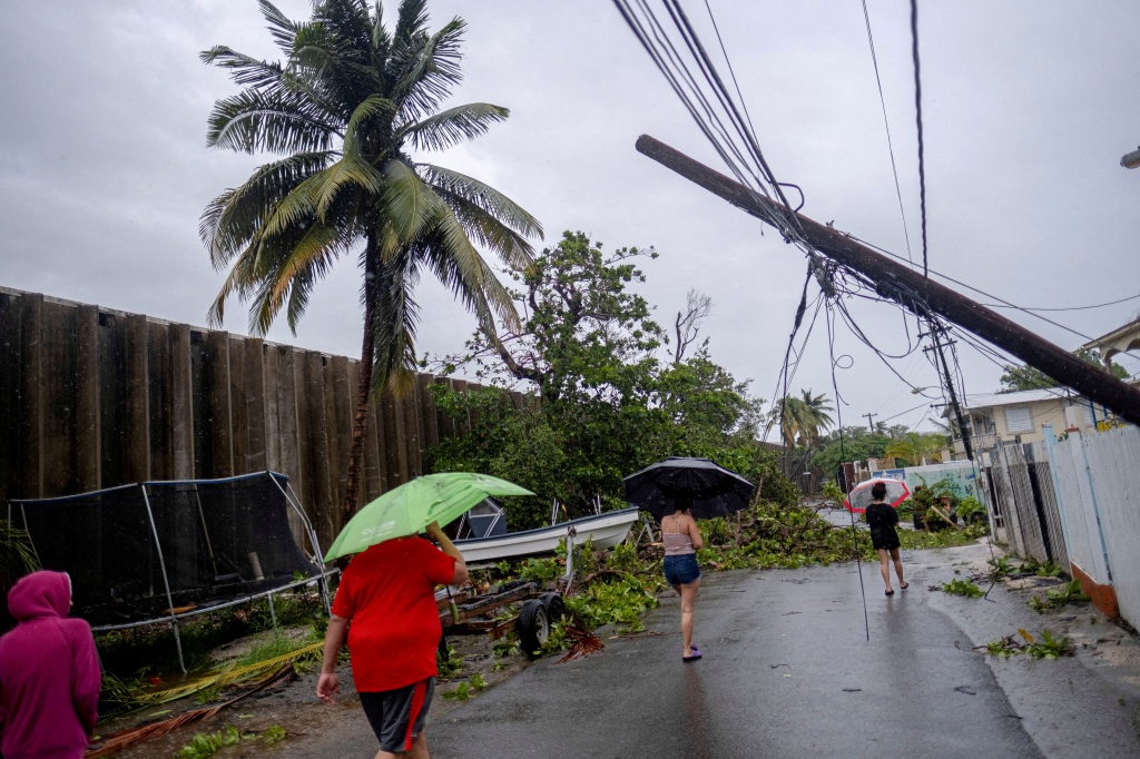 People walk on a street affected by the passing of Hurricane Fiona in Penuelas, Puerto Rico on Sep. 19, 2022.