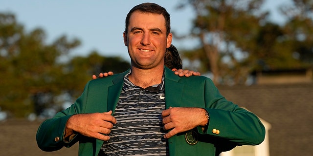 Hideki Matsuyama, of Japan, helps Scottie Scheffler put on the green jacket after winning the 86th Masters golf tournament on Sunday, April 10, 2022, in Augusta, Ga.