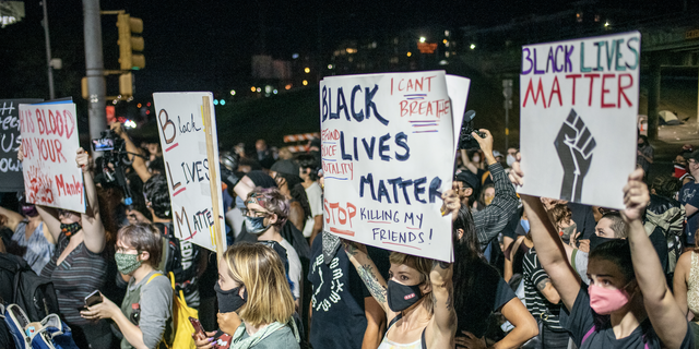 People hold up signs outside Austin Police Department after a vigil for Garrett Foster on July 26, 2020 in downtown Austin, Texas. 