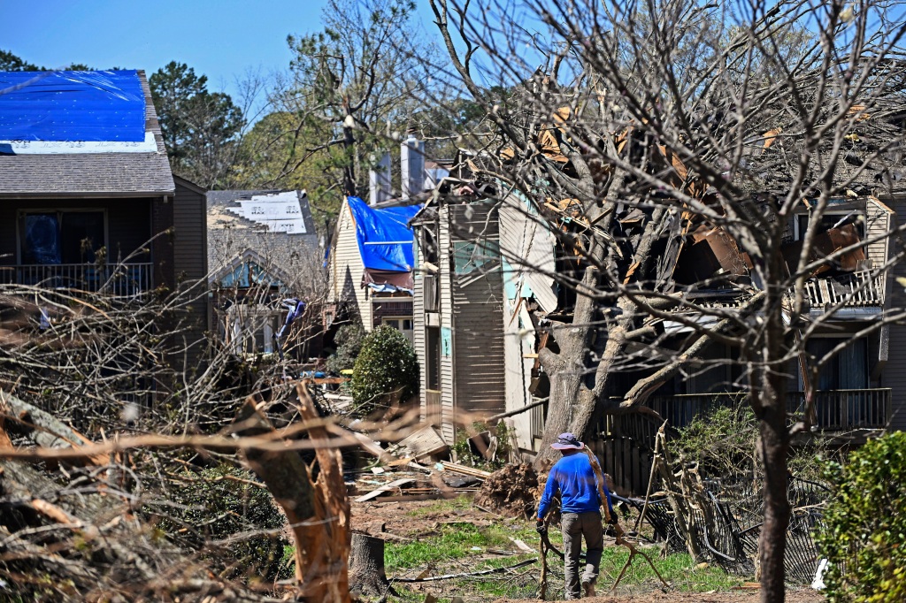 A man drags tree limbs to a pile at the Foxcroft Woods Condominiums on April 2, 2023, in Little Rock, Ark.