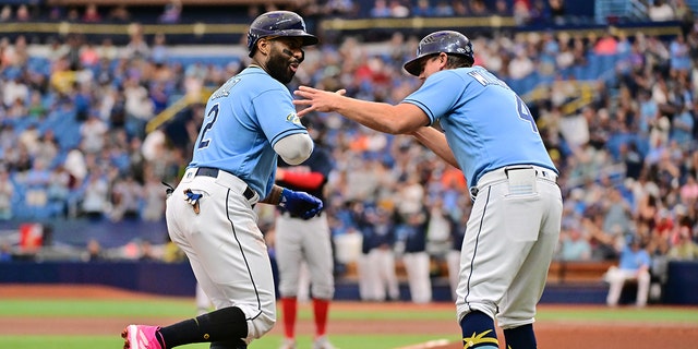 Yandy Diaz (2) of the Tampa Bay Rays celebrates with third base coach Brady Williams (4) after hitting a home run in the first inning against the Boston Red Sox at Tropicana Field April 13, 2023, in St Petersburg, Fla.