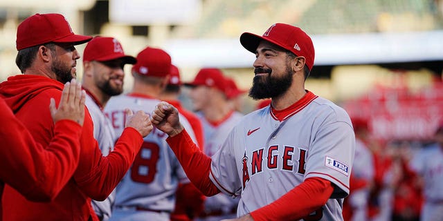 Anthony Rendon of the Los Angeles Angels, right, fist-bumps coaches and teammates during a game against the Oakland Athletics at RingCentral Coliseum Thursday, March 30, 2023, in Oakland, Calif. 