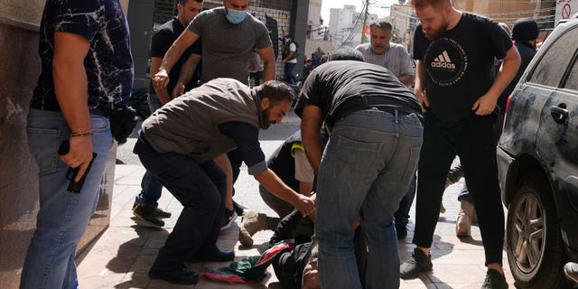 Supporters of a Shiite group allied with Hezbollah call for help for an injured comrade during armed clashes that erupted during a protest in the southern Beirut suburb of Dahiyeh, Lebanon Oct. 14, 2021. 