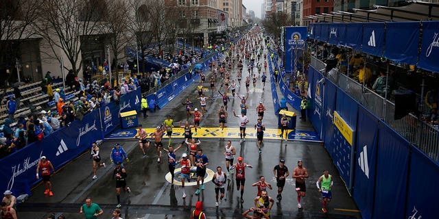 Runners stream down Boylston Street as rain falls on the 127th Boston Marathon.