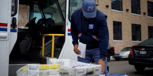 A worker loads mail into a delivery vehicle outside a United States Postal Service (USPS) distribution center in Chicago, Illinois, U.S., on Tuesday, Oct. 12, 2021. 