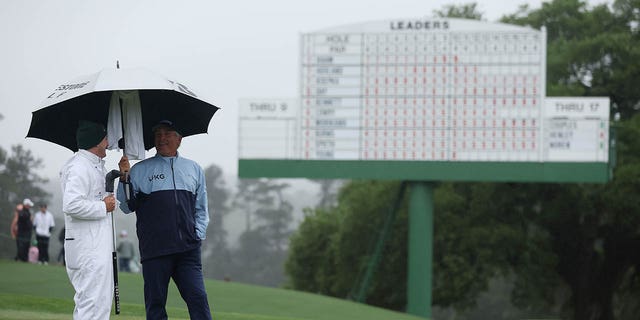 Fred Couples of the United States looks on from the 18th green with his caddie, George Downing, during the continuation of the weather-delayed second round of the 2023 Masters Tournament at Augusta National Golf Club on April 8, 2023, in Augusta, Georgia. 