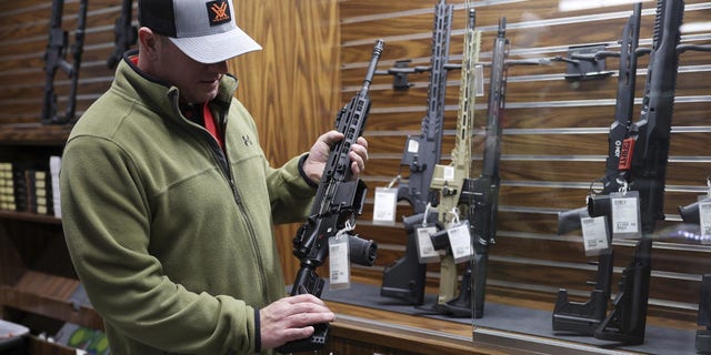 A firearm store owner shows off a Heckler & Koch brand rifle