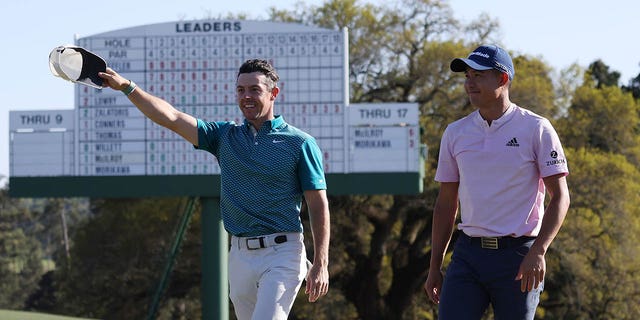 Rory McIlroy, left, and Collin Morikawa acknowledge fans as they walk off the 18th green after finishing their round during the final round of the Masters at Augusta National Golf Club April 10, 2022, in Augusta, Ga. 