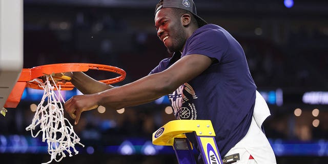 Adama Sanogo of the Connecticut Huskies cuts down a piece of a net after defeating the San Diego State Aztecs 76-59 in the NCAA men's national championship game at NRG Stadium April 3, 2023, in Houston.