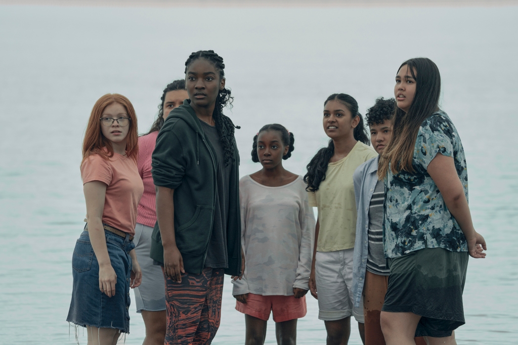 Allie (Halle Bush) with a group of other young women who have "The Power" to electrocute at will. They're standing outside on a beach; all of them are looking at something off-camera.