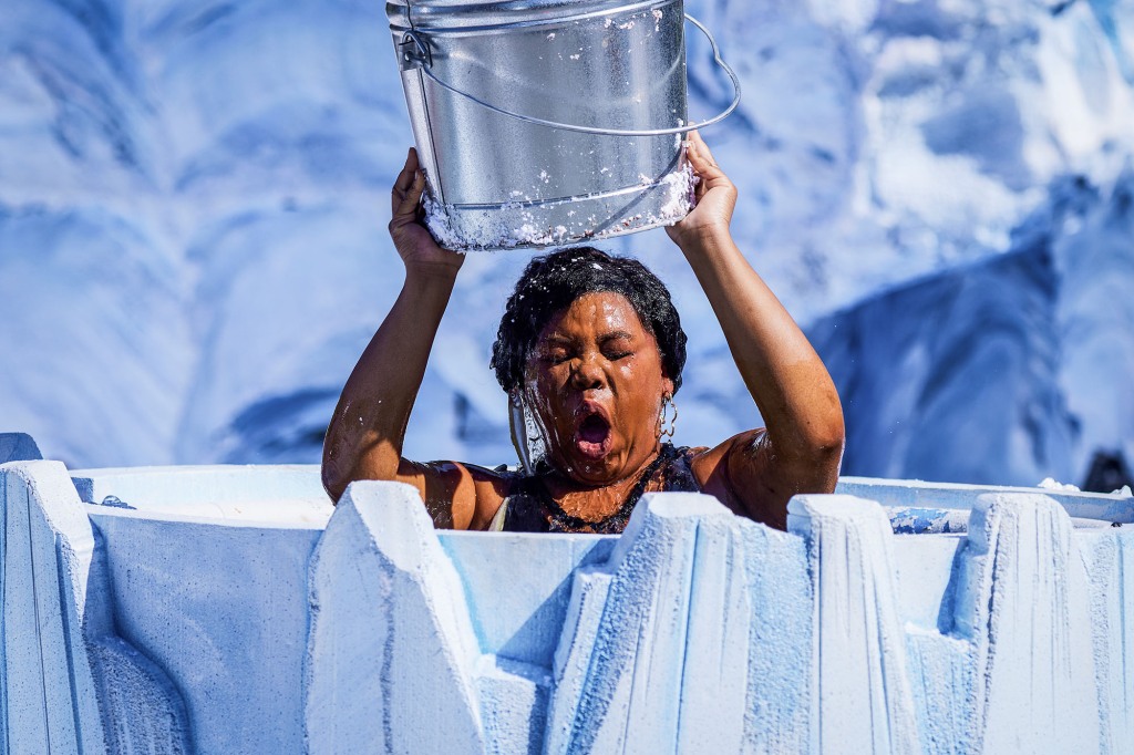 A contestant. She's holding a silver bucket of water over hear head and her eyes are closed. The water is streaming down her face and her mouth is wide open in shock.