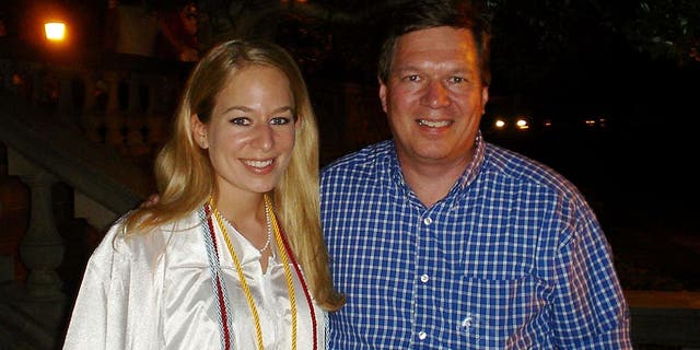 Natalee is in a white cap and gown as she stands with her father, Dave