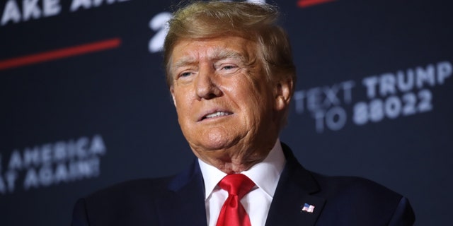 Donald Trump in front of dark blue campaign backdrop