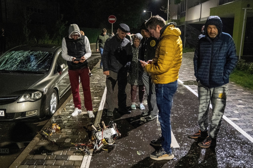 Local residents inspect a part of a suicide drone that was shot down during Russia's overnight attack in Kyiv, Ukraine, on May 8, 2023.