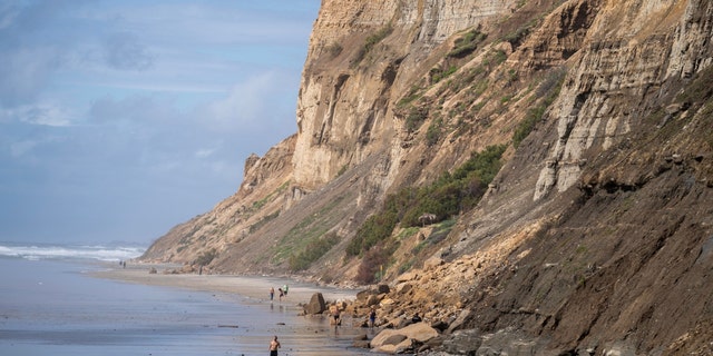 People move past a San Diego, California, bluff collapse