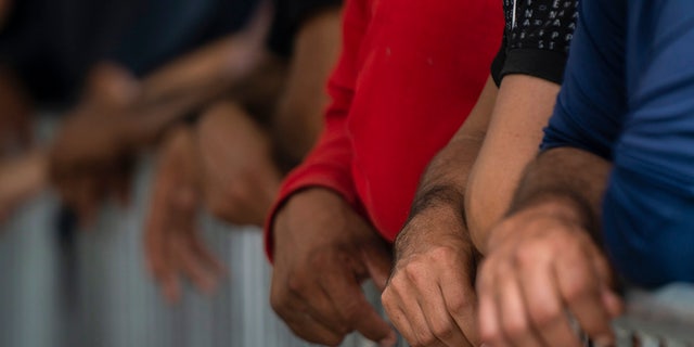 Migrants' hands on gate by port of enntry