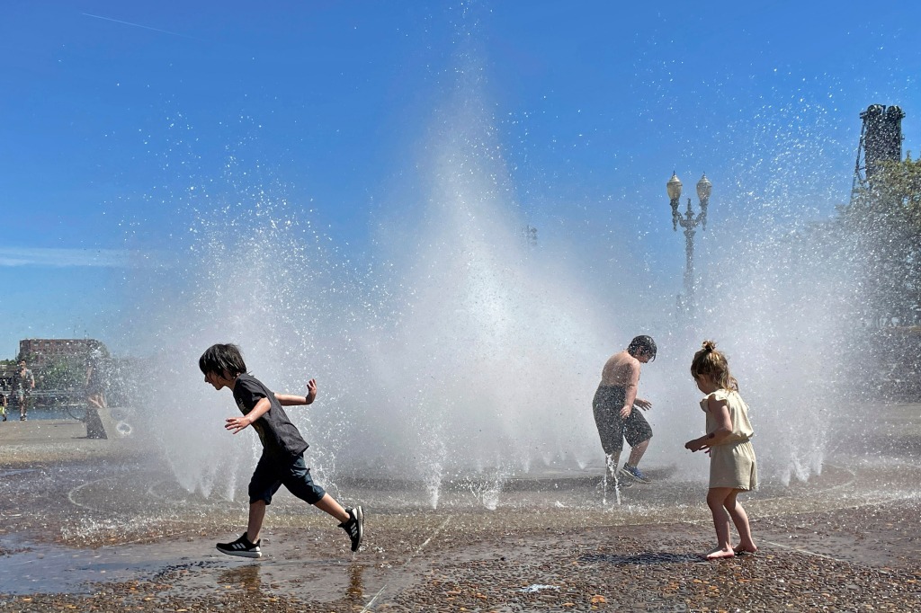 Children play in a fountain to cool off in downtown Portland, Ore., o May 12, 2023. 