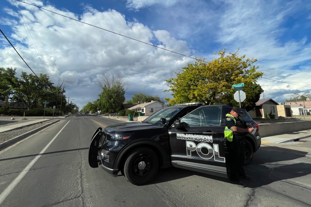 A police officer blocks traffic on a road after the deadly shooting on May 15, 2023, in Farmington, New Mexico.