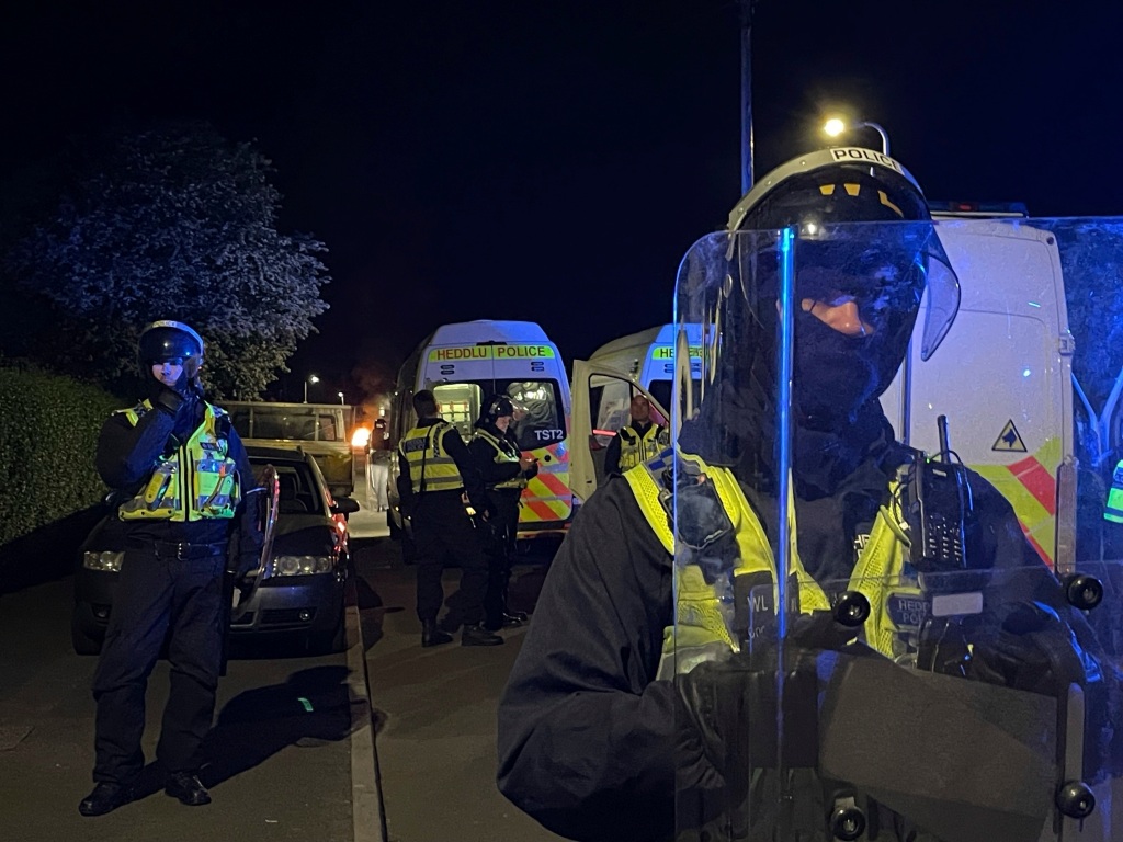 Police officers stand guard on Howell Road in Cardiff as they face a "large scale disorder" at the scene of a road traffic collision on Snowden Road in Ely, Cardiff, on May 23, 2023.  