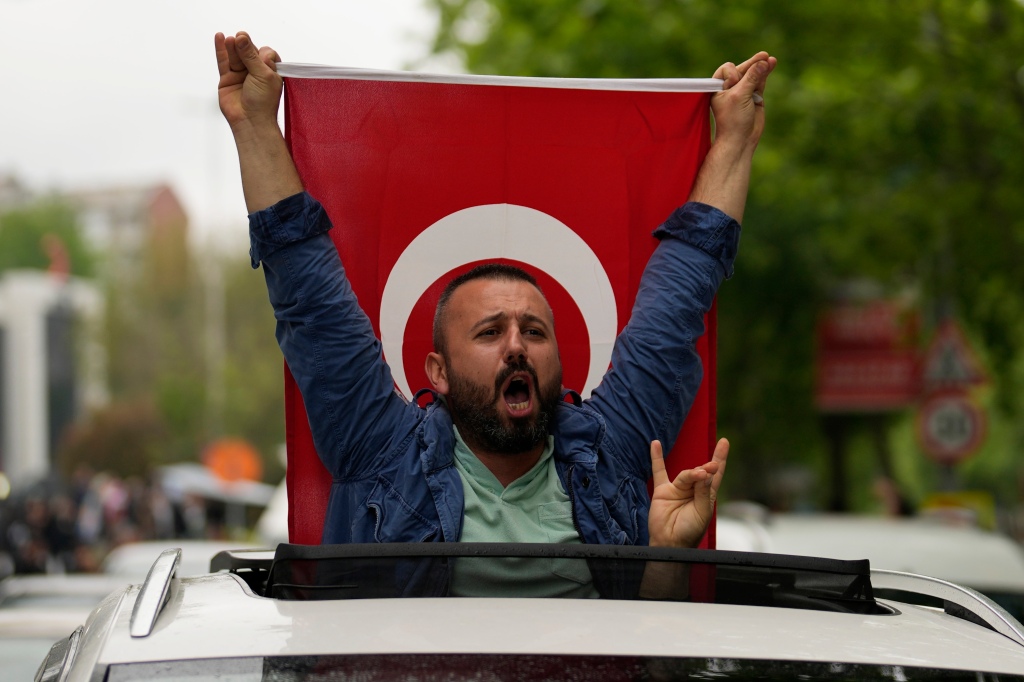 A supporter of the President Recep Tayyip Erdogan holding a Turkish flag shouts slogans outside AK Party offices.
