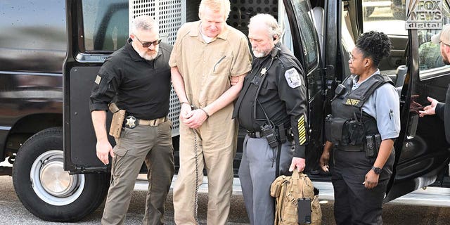 Alex Murdaugh is escorted into the courthouse wearing a tan prison jumpsuit.