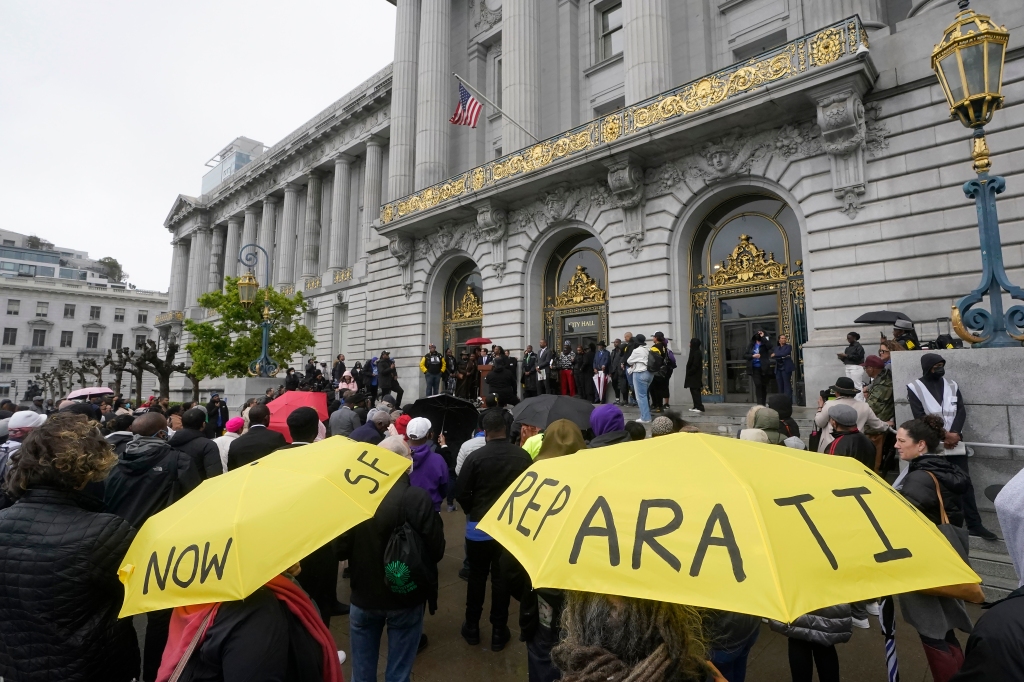 A crowd listens to speakers at a reparations rally outside of City Hall in San Francisco on March 14, 2023. 