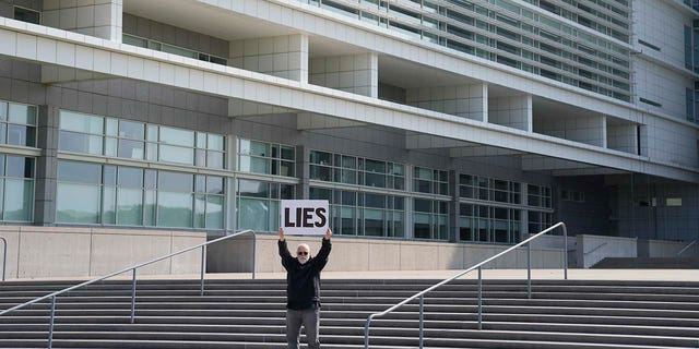 Bill Christeson holds up a sign on the steps of the federal courthouse in Central Islip