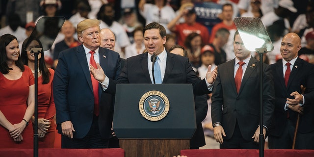 Trump standing behind Ron DeSantis on stage