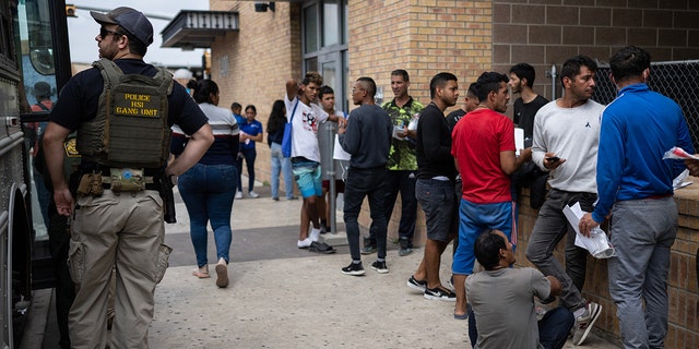 Migrants in a line near a bus in Texas