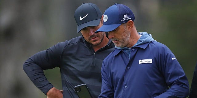 Brooks Koepka and coach Claude Harmon III talk during a practice round at the 2020 PGA Championship