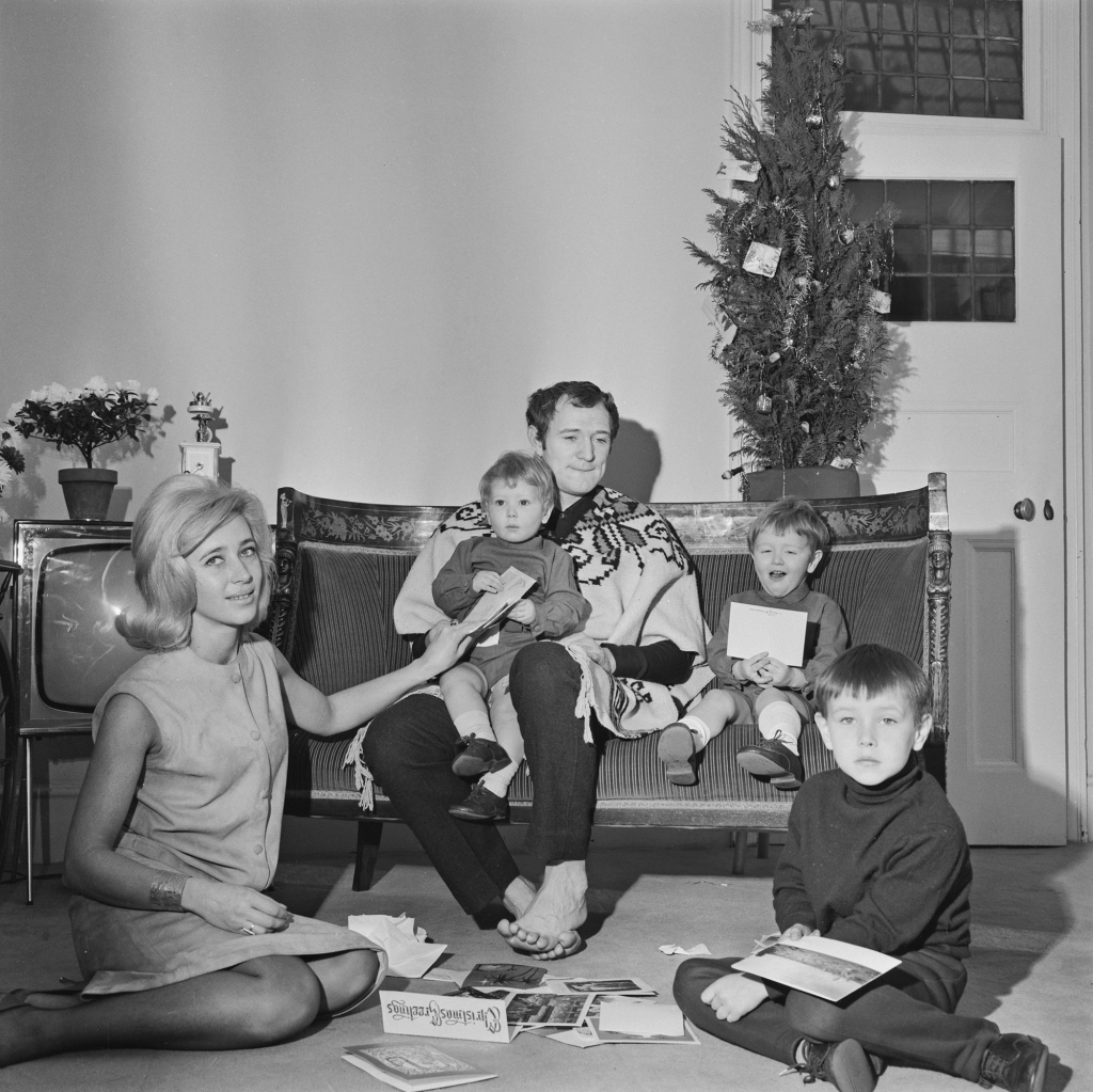 A black-and-white photo showing Richard Harris at home in 1964 with his wife Elizabeth Reese-Williams and small sons Jamie, Jared and Damian.