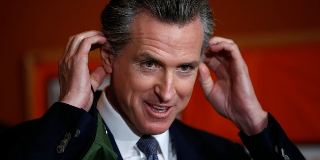 Democratic California Gov. Gavin Newsom removes his mask before a press conference.