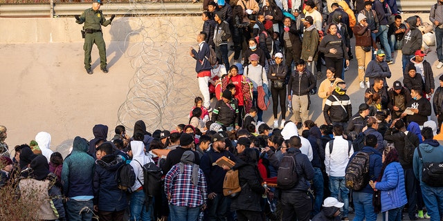 Border Patrol agent and migrants at the border