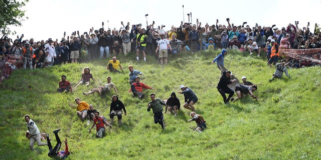 Competitors chase after a cheese wheel during the annual cheese rolling race in the uk