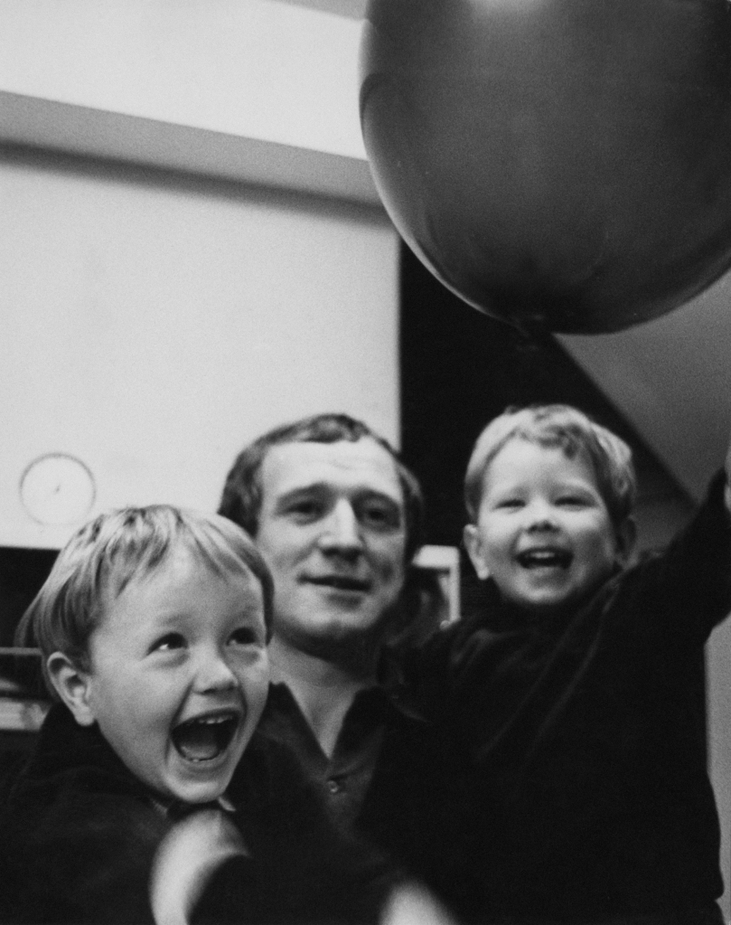 Black and white photo from 1966 showing Richard Harris with his sons Jared and Damian. They're all smiling for the camera.