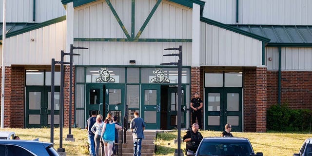 Law enforcement stand outside of Henryetta High School on Monday